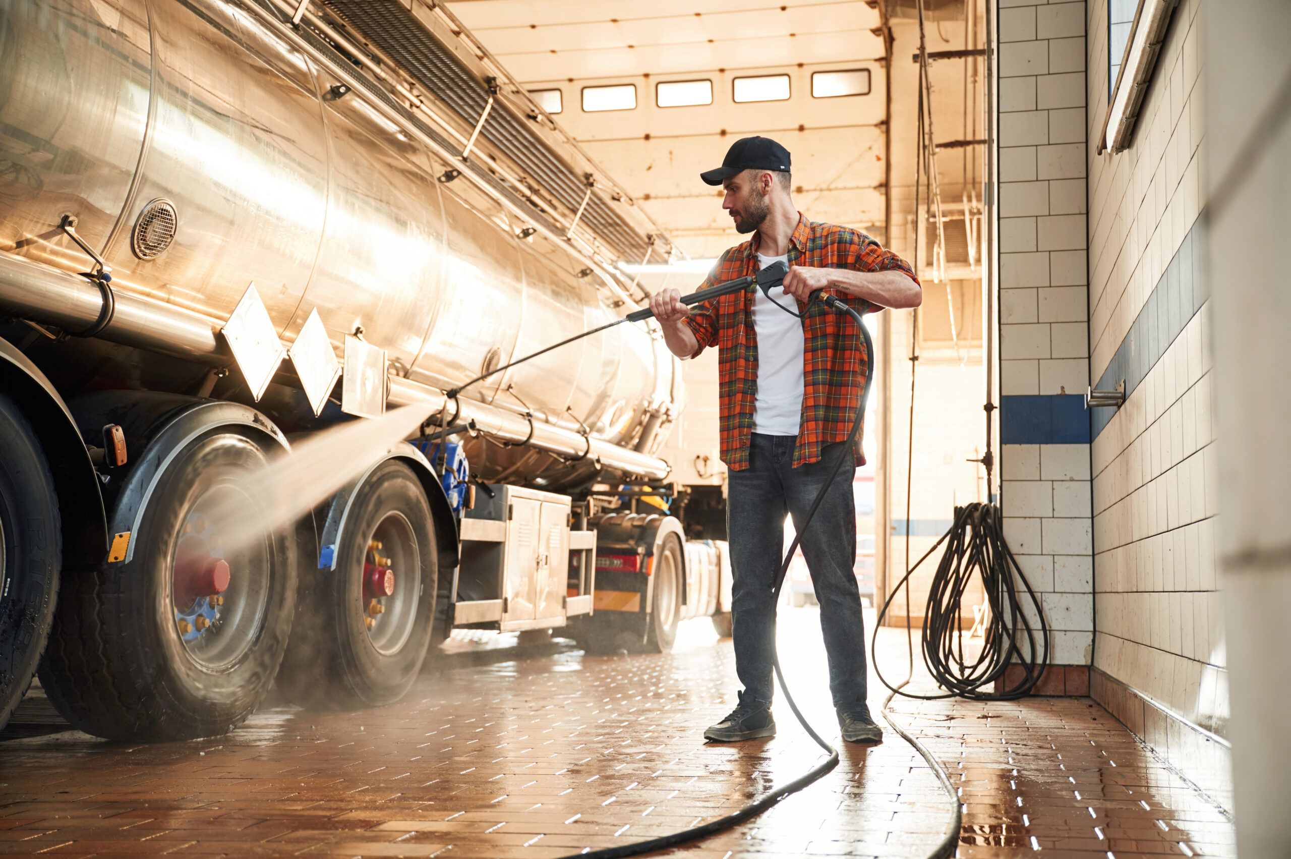 Worker pressure washing commercial truck during spring vehicle cleaning in Essex Ontario